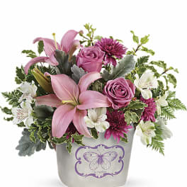 Pink lilies, roses, and white alstroemeria in a butterfly-decorated container