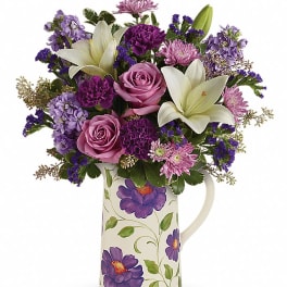 Purple and pink mixed bouquet in a floral ceramic pitcher