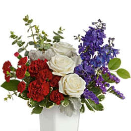 Red and white roses with purple flowers in a white vase