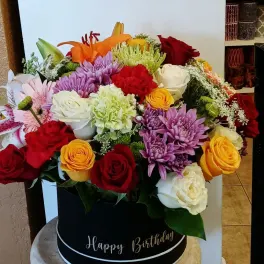 Mixed bouquet in a black hatbox with roses, lilies, and chrysanthemums