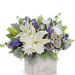 White lilies and purple flowers arranged in a square box