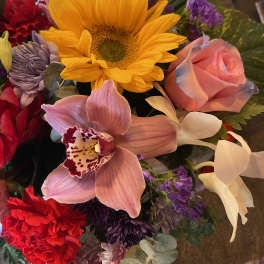 Mixed bouquet with a yellow sunflower, pink rose, and orchids