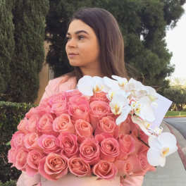 Woman holding a large pink rose box with white orchids