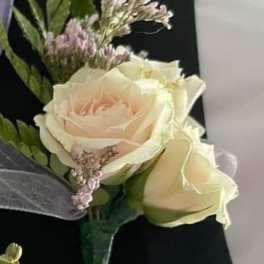 Boutonniere with cream roses and small pink filler flowers