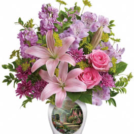 Pink lilies, roses, and purple flowers in a white vase