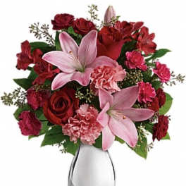 Pink lilies and red roses in a clear glass vase
