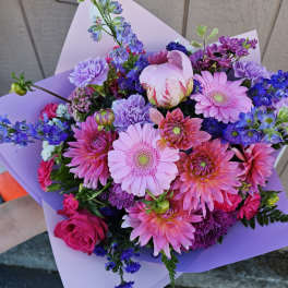 Bouquet of pink, purple, and blue flowers wrapped in lavender paper