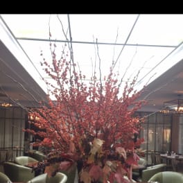 Tall red berry arrangement in a black pedestal vase