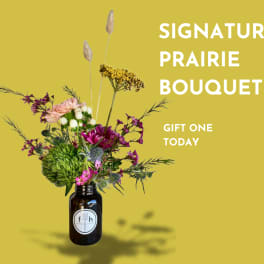 Wildflower bouquet in a dark glass jar vase on a yellow background