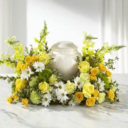 Yellow roses and white daisies arranged around a silver urn