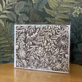 Floral-patterned greeting card in a clear sleeve on a wooden table