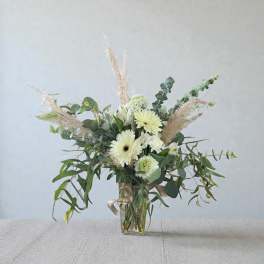 White gerbera daisies and greenery in a clear glass vase