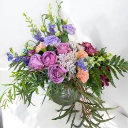 Lavender roses and mixed blooms in a low green vase