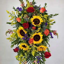 Tall standing floral spray with sunflowers and red roses on an easel