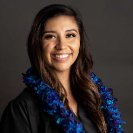 Woman wearing a blue and purple flower lei over a black top