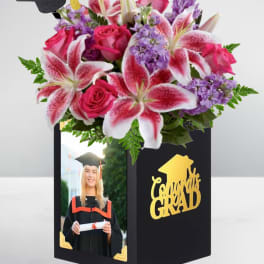 Graduation gift box with pink and purple flowers and a graduation cap topper