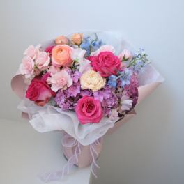 Bouquet of pink and peach roses with pastel filler flowers in wrapping paper