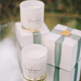 Three white candles and two white gift boxes with green ribbon
