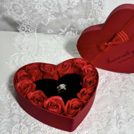 Heart-shaped red gift box with red roses and a ring inside