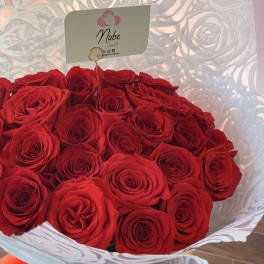 Bouquet of red roses wrapped in white paper with a red ribbon