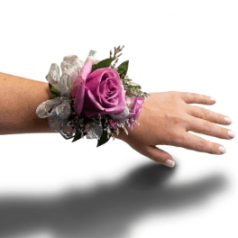Purple rose wrist corsage with silver ribbon on a person’s arm