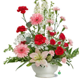 Mixed bouquet of red and pink flowers in a white vase