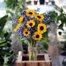 Bouquet of yellow sunflowers and blue flowers in a glass vase