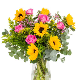 Bouquet of yellow sunflowers and pink roses in a clear glass vase