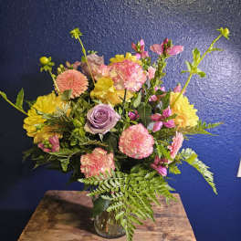 Mixed bouquet in a clear glass vase with pink, yellow, and lavender blooms