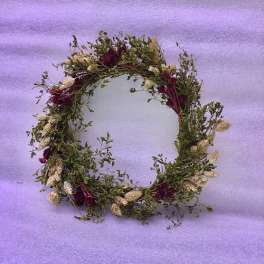 Floral wreath with burgundy and cream dried flowers on a lavender background