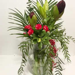 Tropical bouquet with red flowers and green buds in a clear vase