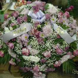 Large pink and white floral wreath with ribbon banners