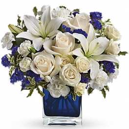 White lilies and roses arranged in a blue glass vase
