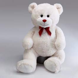 White teddy bear with a red bow sitting on a gray background