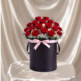 Red roses in a black hatbox with a pink ribbon