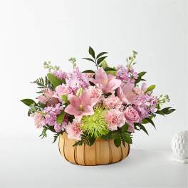 Pink floral arrangement in a woven basket with roses and lilies