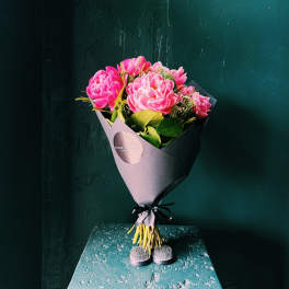 Pink peony bouquet wrapped in dark paper with a black ribbon