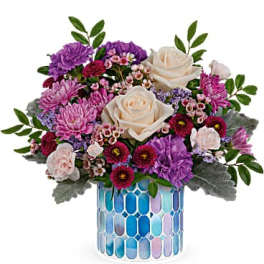 Bouquet of cream roses, purple chrysanthemums, and pink filler flowers in a blue mosaic vase