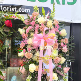 Large pink and cream floral standing spray with ribbon and name accents
