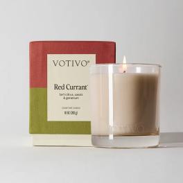 Lit scented candle in a glass tumbler beside its box