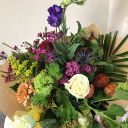 Mixed bouquet with roses, orchids, and other flowers wrapped in brown paper