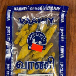 A plastic bag of turmeric roots on a wooden surface.