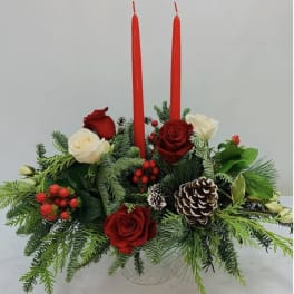Red and white roses with evergreen foliage and two red taper candles