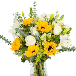 Bouquet of yellow sunflowers and white lilies in a glass vase