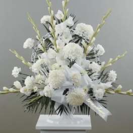 White funeral spray with ribbon on a stand