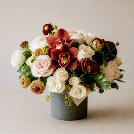 Bouquet of roses and burgundy orchids in a gray vase