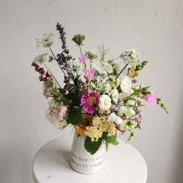 Mixed bouquet in a white ceramic vase with pink, white, and purple flowers