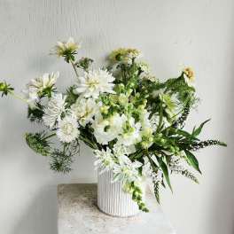 White floral arrangement in a ribbed white vase