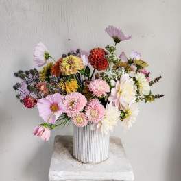 Mixed pastel flowers arranged in a white ribbed vase