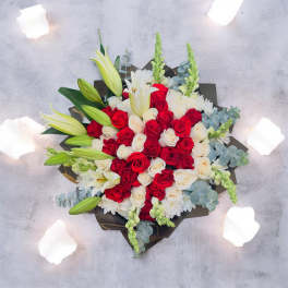 Bouquet of red and white roses with lilies in dark wrapping